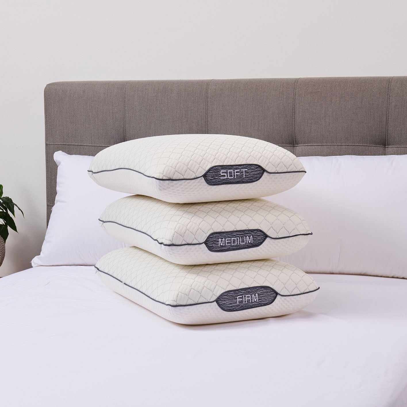 Three memory pillows labeled 'Soft', 'Medium', and 'Firm' stacked on a bed.