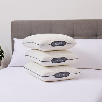 Three memory pillows labeled 'Soft', 'Medium', and 'Firm' stacked on a bed.